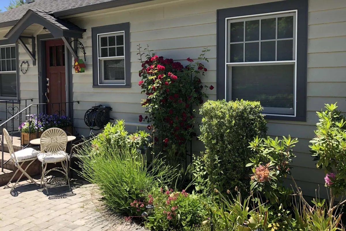 An inviting exterior view of the cottage’s front door, surrounded by blooming flowers and cozy outdoor seating. The image suggests a welcoming home base, perfect for relaxing before or after a night out on the town.