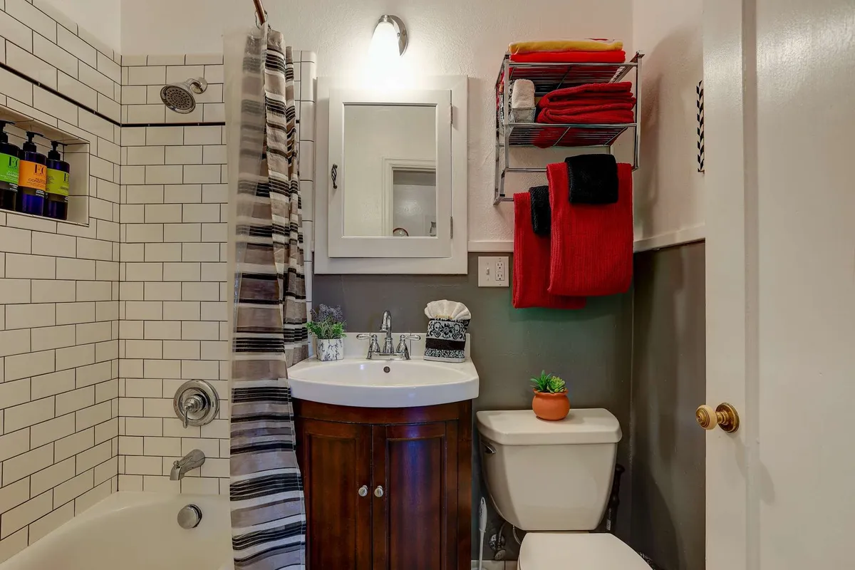 This image displays a cozy, well-lit bathroom interior featuring a clean shower area, a modern sink, a neatly organized towel rack with fluffy towels, and a mirror. The overall ambiance is inviting, suggesting a relaxing and spa-like environment ideal for unwinding after outdoor activities.